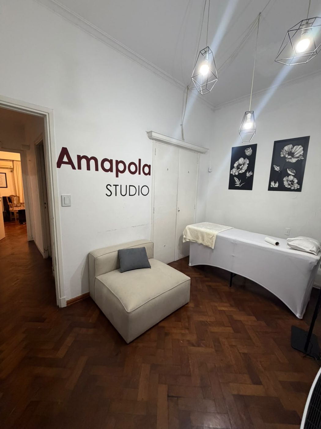 Recepción de Amapola Studio con el logo en la pared y la camilla al fondo